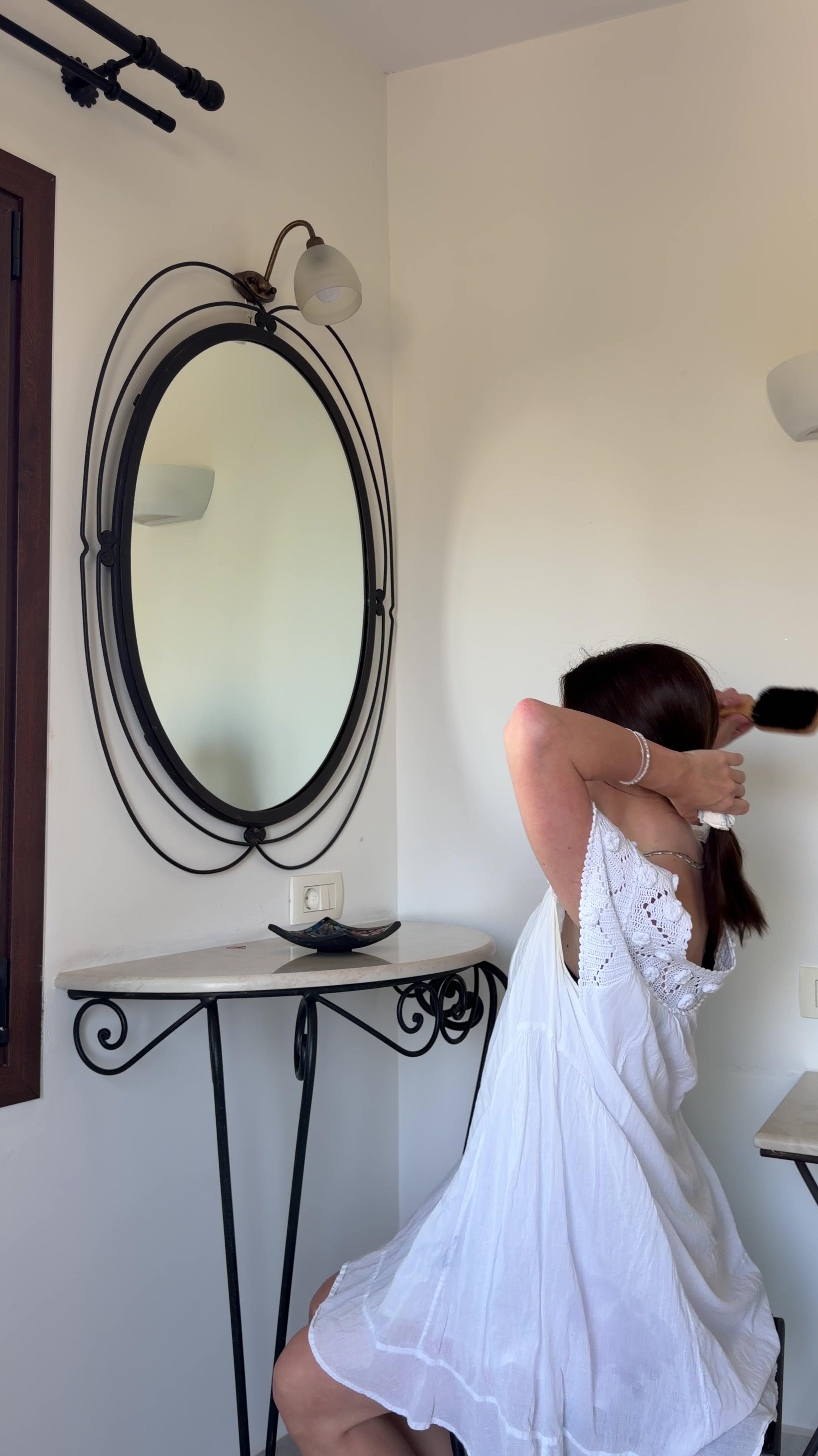 Woman Styling Hair in Front of Vanity Mirror